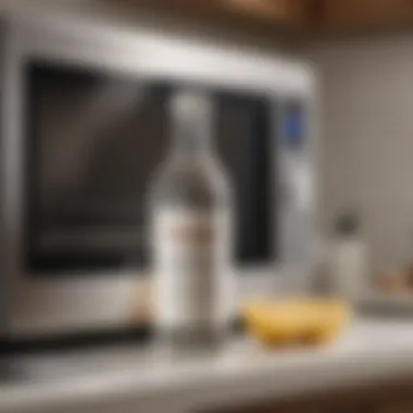 A bottle of white vinegar placed next to a microwave